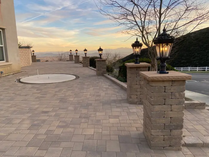 Paver patio with stone pillars and lanterns at sunset