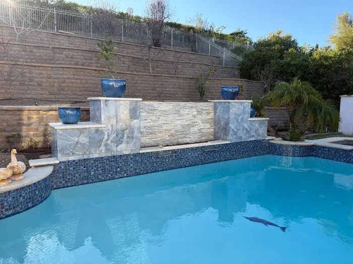 Pool with stone water wall, sheer descents and blue planters
